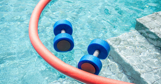 Foam pool noodle and water exercise dumbbells floating in a swimming pool, commonly used for aquatic fitness and rehabilitation.